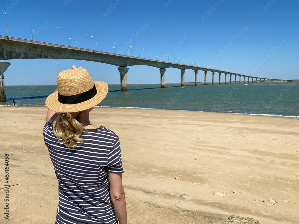 Woman looking at the bridge over the sea in the Atlantic ocean on the Ile de Ré in La Rochelle.