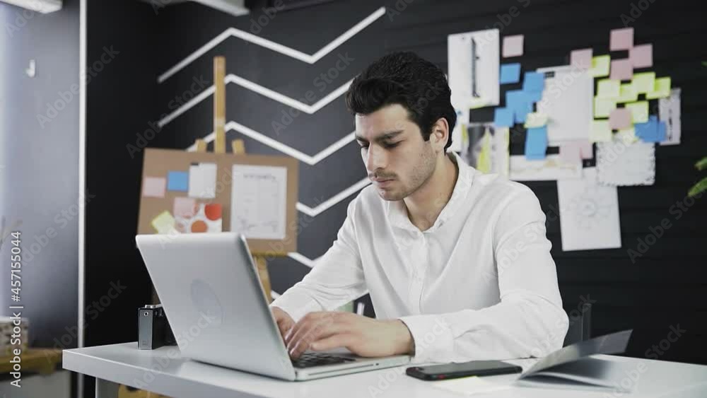 A young man of Caucasian appearance is sitting at a computer. Remote work. Freelance. Zooming in on the camera A young man of Caucasian appearance is sitting at a computer. Remote work. Freelance. Zooming in on the camera