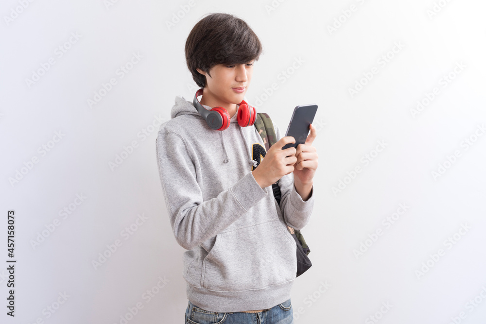 European teen boy student texting or playing game online on smartphone isolate on white background. European teen boy student texting or playing game online on smartphone isolate on white background.