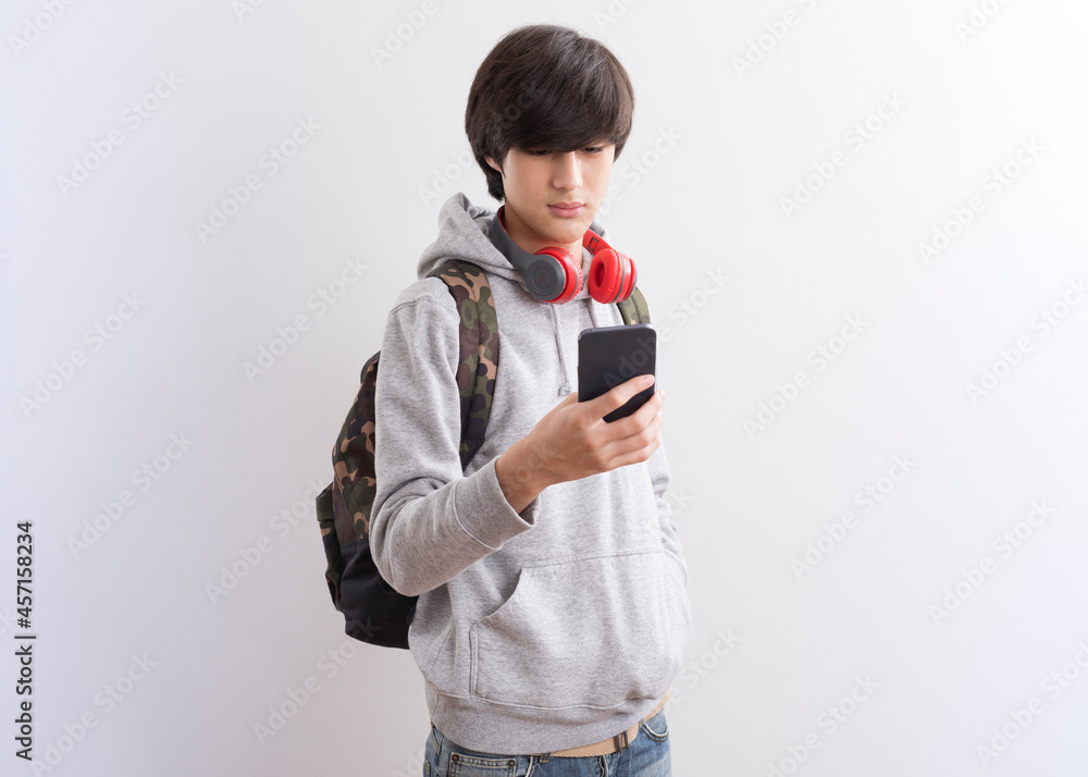 European teen boy student texting or playing game online on smartphone isolate on white background. European teen boy student texting or playing game online on smartphone isolate on white background.