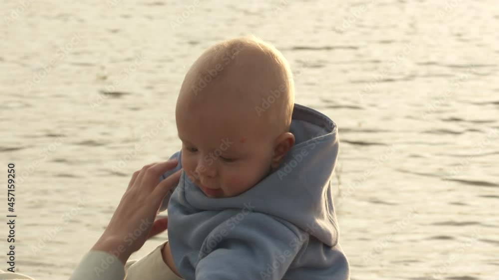 Mother and child against streak of glittering light reaching across the water, mom with baby shining in backlighting of sunset, family vacations adventure. High quality 4k footage Mother and child against streak of glittering light reaching across the water, mom with baby shining in backlighting of sunset, family vacations adventure. High quality 4k footage