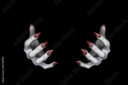 Photo Bony pale hands of vampire or monster with sharp bloody red nails in the dark