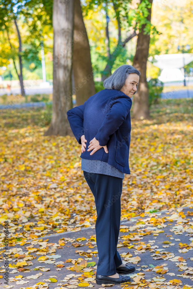Senior woman suffering from backache outdoors Senior woman suffering from backache outdoors