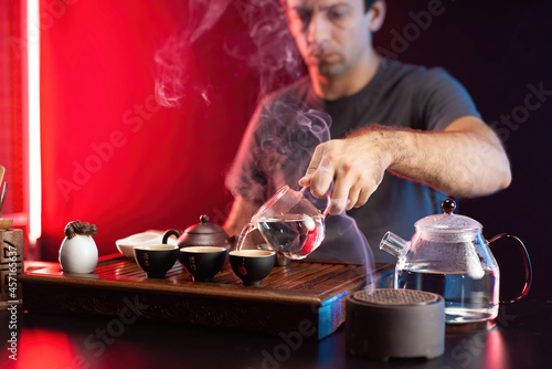 a man makes tea at a tea table with appliances according to the traditional Chinese tradition