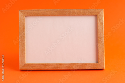 Close up of mockup template white frame with wooden borders on orange blurred background and copy space. Holiday autumn concept backdrop photo