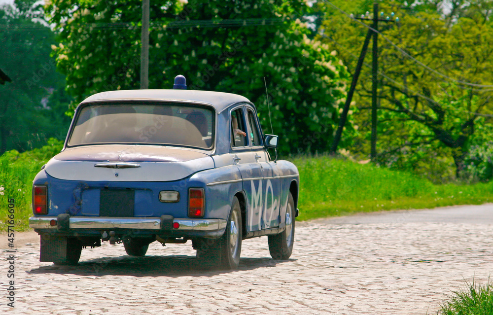 Obraz na płótnie Stary polski samochód milicji obywatelskiej na wiejskiej brukowej drodze w salonie