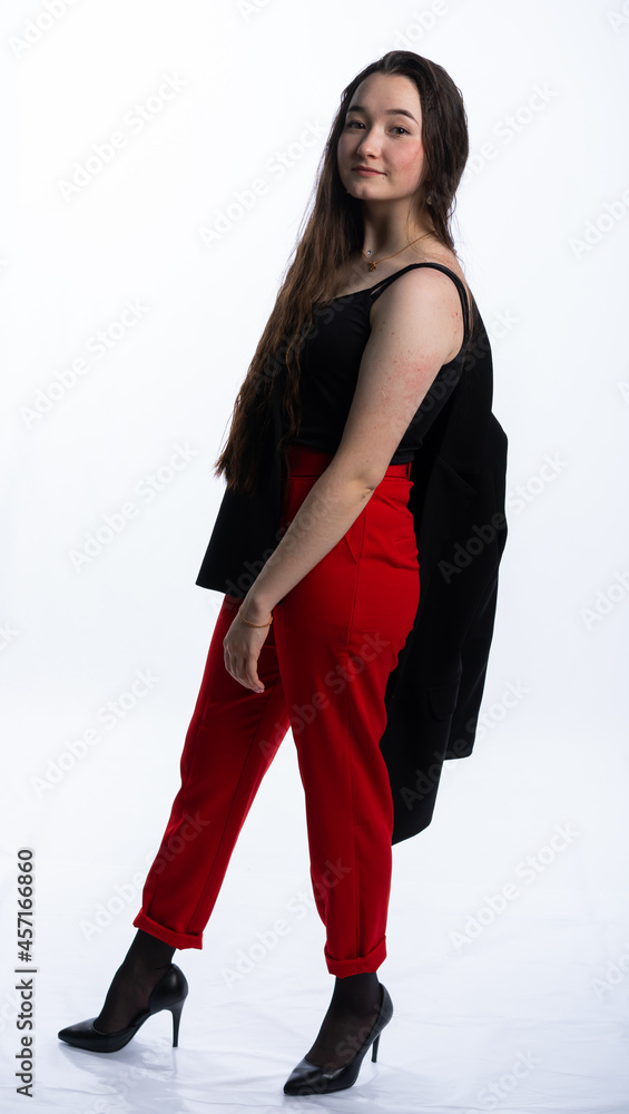 full-length portrait of a girl. model in red trousers, black shoes and a jacket. long curly hair. white, isolated background. acne full-length portrait of a girl. model in red trousers, black shoes and a jacket. long curly hair. white, isolated background. acne