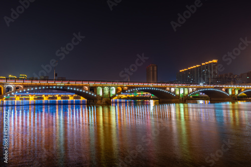 In the city at night, colorful lights are reflected in the water of the river