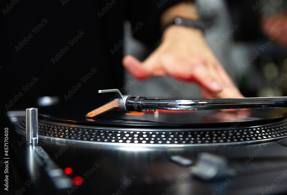 Disc jockey scratching vinyl records with turntable player on party in night club. Professional hip hop dj scratches record on turn table device 