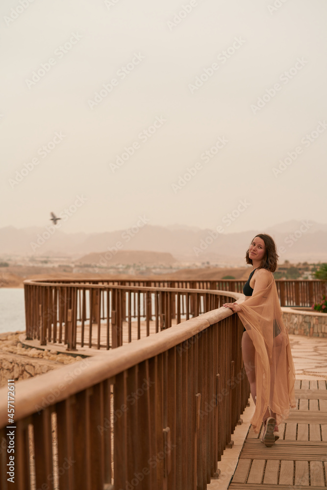 Pretty woman posing in Egypt hotel. Young caucasian woman in black swimsuit and golden dress