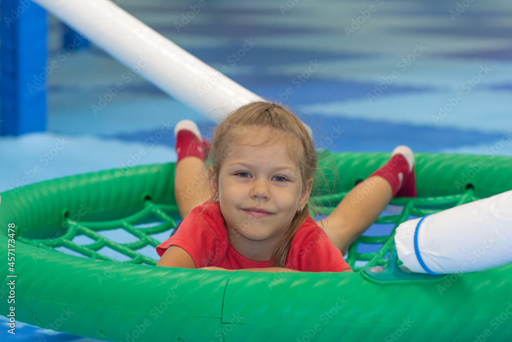 Caucasian little girl of five years old lying on round swing looking at camera in play center Caucasian little girl of five years old lying on round swing looking at camera in play center