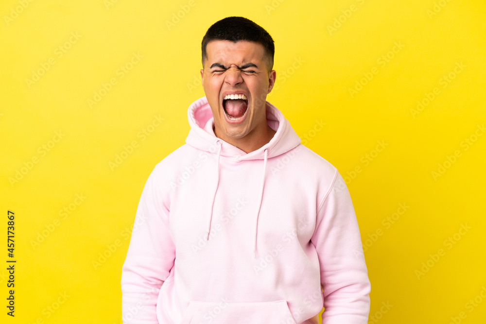 Young handsome man over isolated yellow background shouting to the front with mouth wide open Young handsome man over isolated yellow background shouting to the front with mouth wide open
