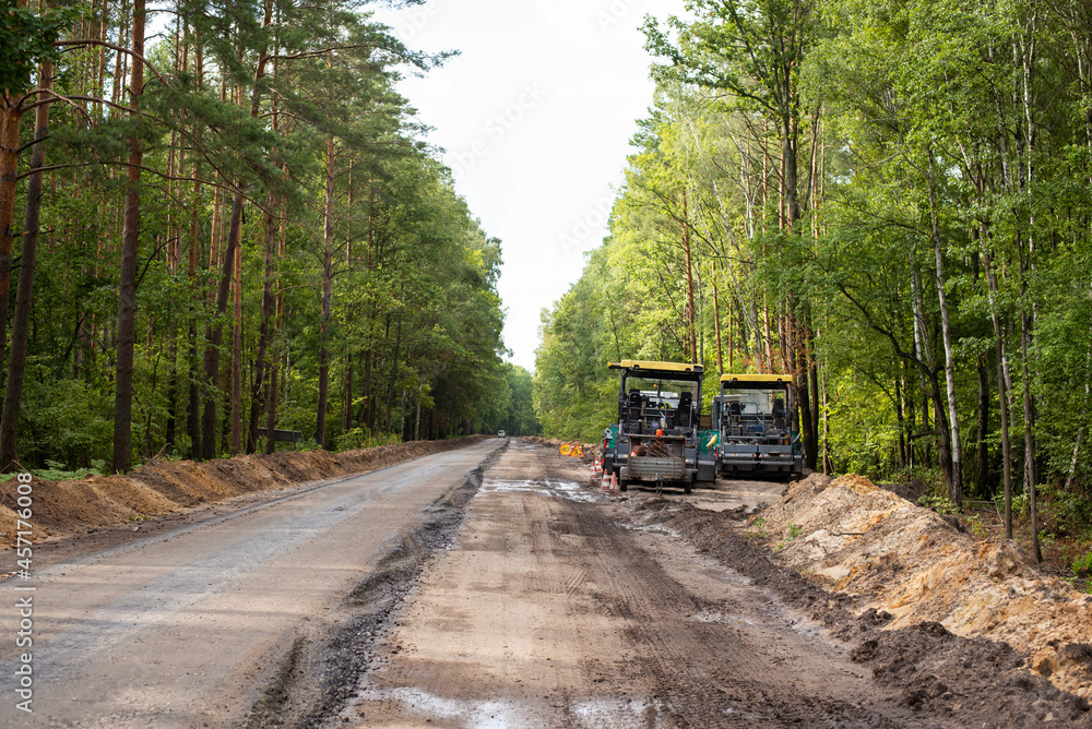 Constructing new asphalt roads. Modern road repairing equipment near new constructed line of high quality asphalt