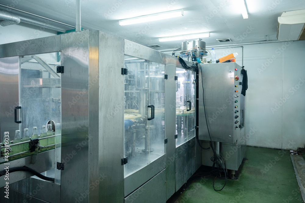 Beverage bottling room with automatic machinery and control panel in production line at processing factory Beverage bottling room with automatic machinery and control panel in production line at processing factory
