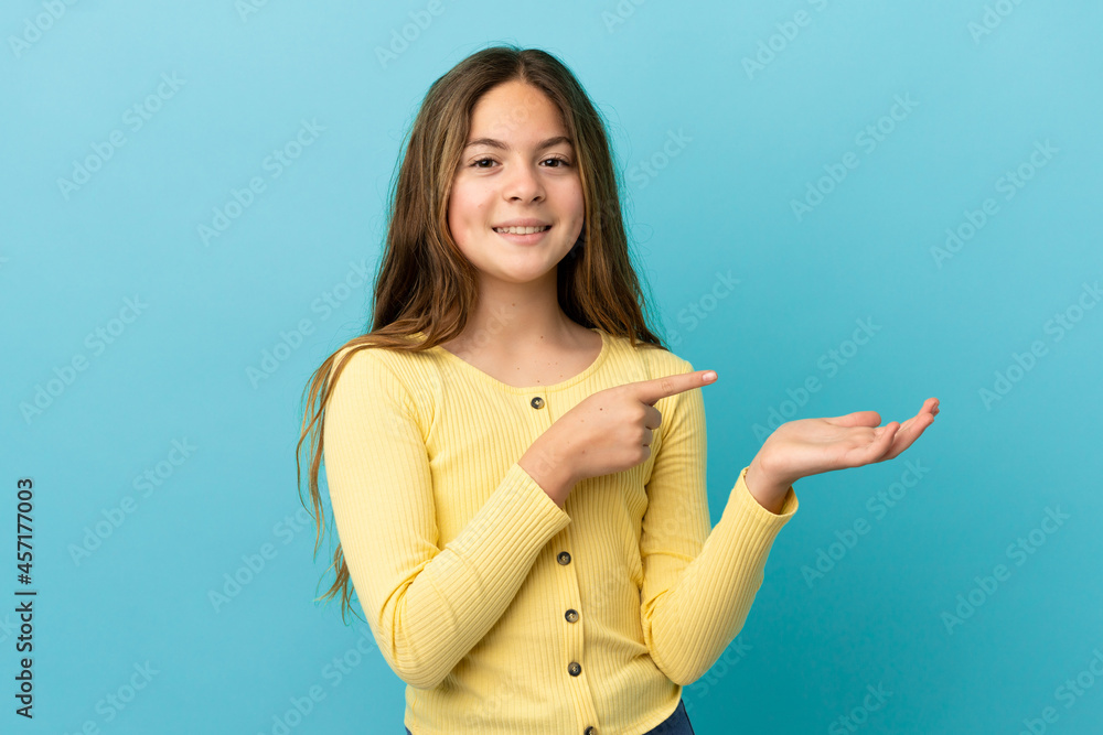 Little caucasian girl isolated on blue background holding copyspace imaginary on the palm to insert an ad Little caucasian girl isolated on blue background holding copyspace imaginary on the palm to insert an ad
