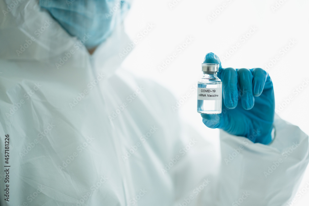 Unrecognizable specialist doctor in a medical PPE suit showing a coronavirus SARS 2019-nCoV or COVID-19 mRNA vaccine. Unrecognizable specialist doctor in a medical PPE suit showing a coronavirus SARS 2019-nCoV or COVID-19 mRNA vaccine.