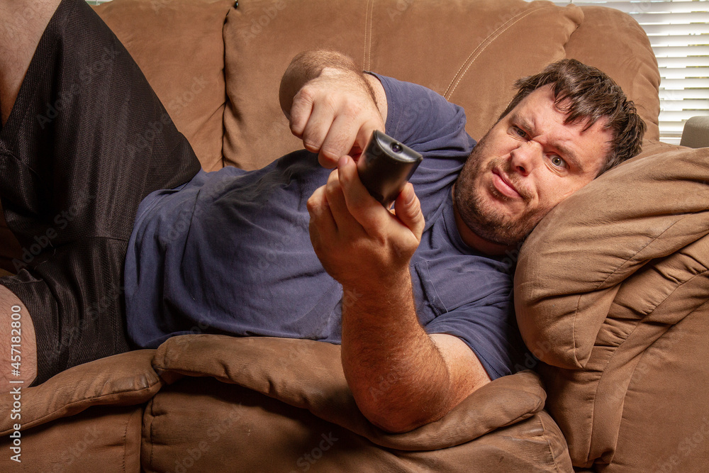 Fototapeta premium confused man trying to push buttons on the remote for the tv