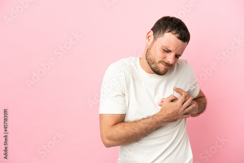 Young Brazilian man isolated on pink background having a pain in the heart