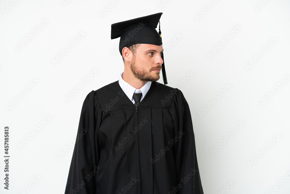 Young university Brazilian graduate isolated on white background looking to the side Young university Brazilian graduate isolated on white background looking to the side