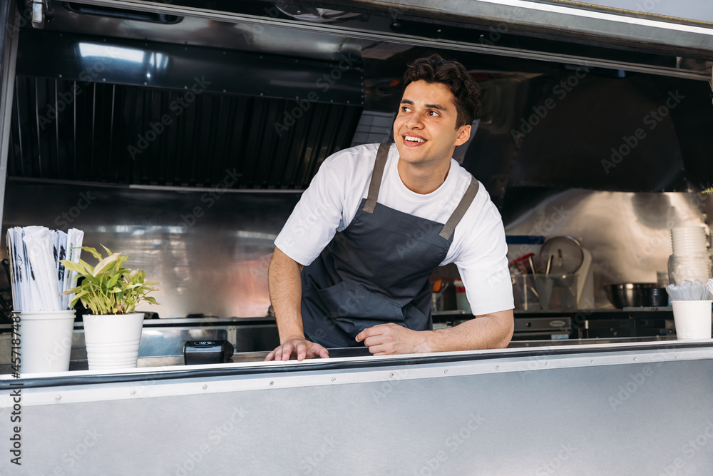 Portrait of a smiling food truck owner wearing apron leaning counter Portrait of a smiling food truck owner wearing apron leaning counter