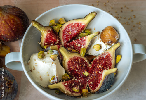 White bowl with purple figs, fresh cheese, honey, pistachios and sesame seeds 