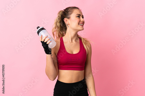 Young Brazilian woman isolated on pink background with sports water bottle © luismolinero