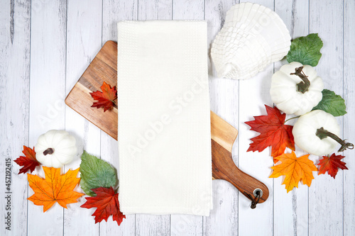 Tea towel dish cloth product mockup. Thanksgiving farmhouse theme with turkey, white pumpkins and autumn fall leaves, on a white wood background. Negative copy space. photo