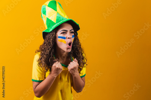 Brazilian fan. Brazilian fan celebrating football or soccer game on yellow background. Colors of Brazil. photo