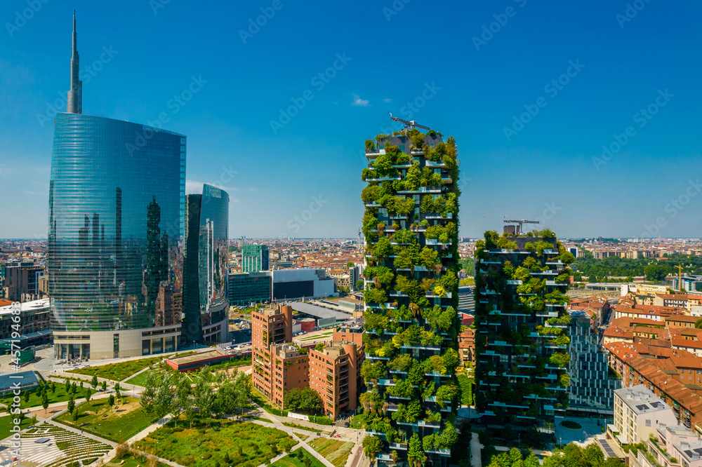 Naklejka premium Aerial view of building called Bosco Verticale in front of office buildings. Vertical Forest, in Milan, Porta Nuova district. Residential buildings with many trees and other plants in balconies