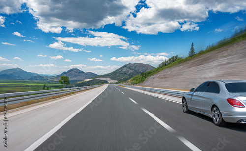 Grey car on a scenic road. Car on the road surrounded by a magnificent natural landscape.