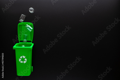 Wallpaper Mural Precycling glass. Bin container for disposal garbage waste and save environment. Green dustbin for recycle glass can trash on black background. Flat lay. Torontodigital.ca
