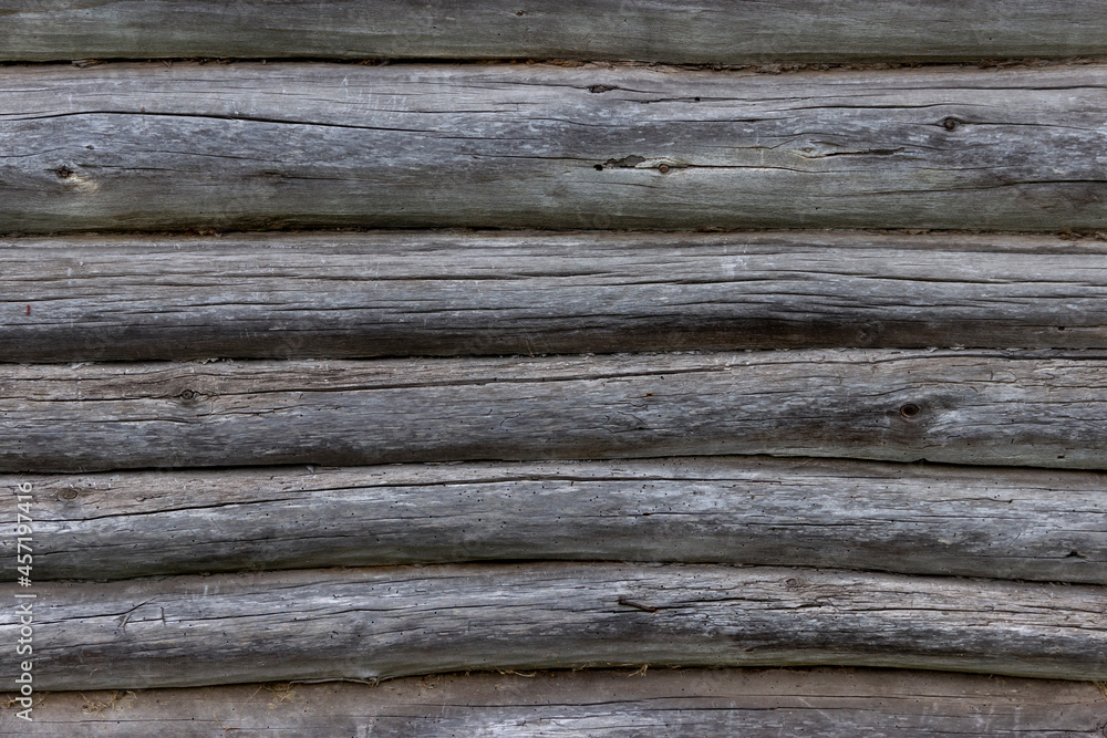The wall of an old wooden house made of darkened weathered logs. Traditional Russian log hut. The wall of an old wooden house made of darkened weathered logs. Traditional Russian log hut.