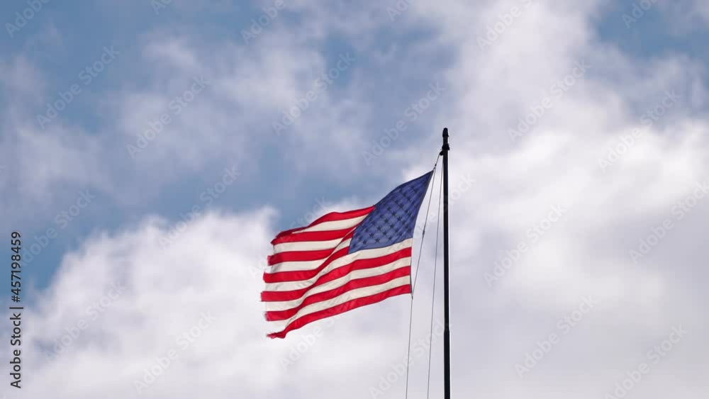 A tattered or weathered American Flag with red and white stripes and 50 stars flaps in the wind with a damaged ragged edge as a symbol of freedom in the United States of America. A tattered or weathered American Flag with red and white stripes and 50 stars flaps in the wind with a damaged ragged edge as a symbol of freedom in the United States of America.