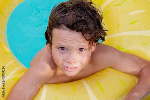 Happy holiday time. Boy having fun in pool with float. Face emotions. Summer vibes.