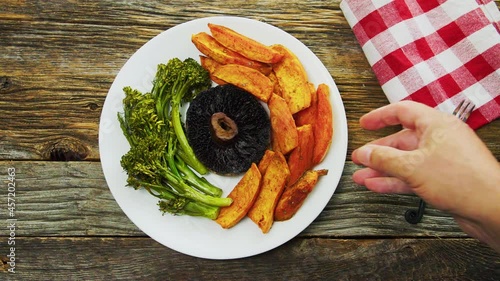 Person is adding plate with baked broccoli, portabello mushroom and sweet potato to wooden rustic table photo