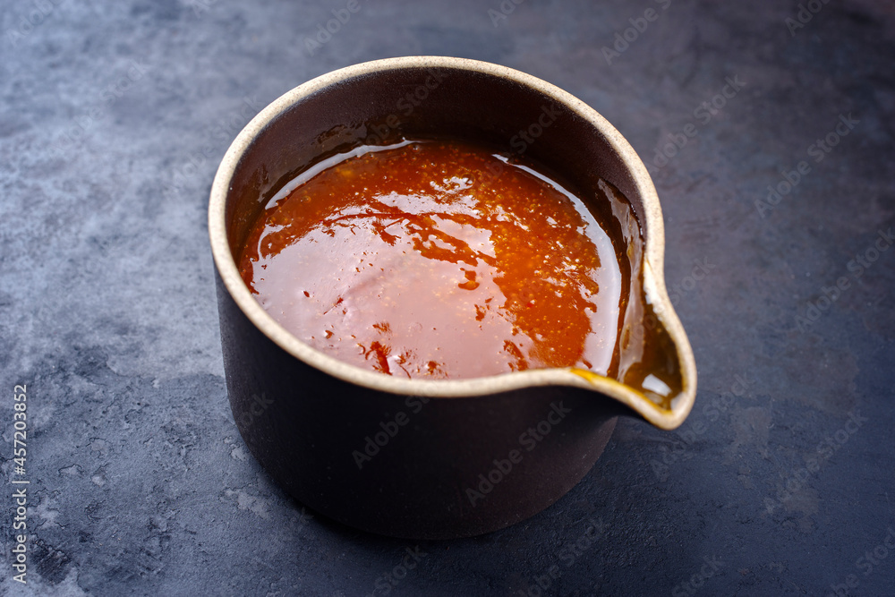 Modern style traditional hot sauce with cayenne peppers and vinegar as Louisiana style for smoked barbecue beef briskets as ingredient served as close-up in a design bowl Modern style traditional hot sauce with cayenne peppers and vinegar as Louisiana style for smoked barbecue beef briskets as ingredient served as close-up in a design bowl