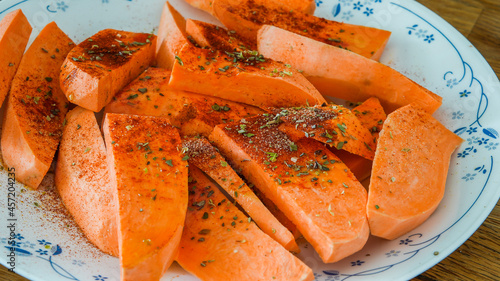 Sweet potao with seasoning on plate ready for cooking photo