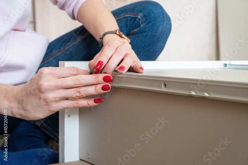 Woman assembling flat pack furniture DIY at home. Bought furniture through online store