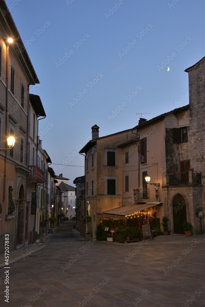 Sunset view of Piazza San Francesco and down via Roma in the quaint town of San Gemini, Italy, a clear late evening sky with waxing crescent moon in the background