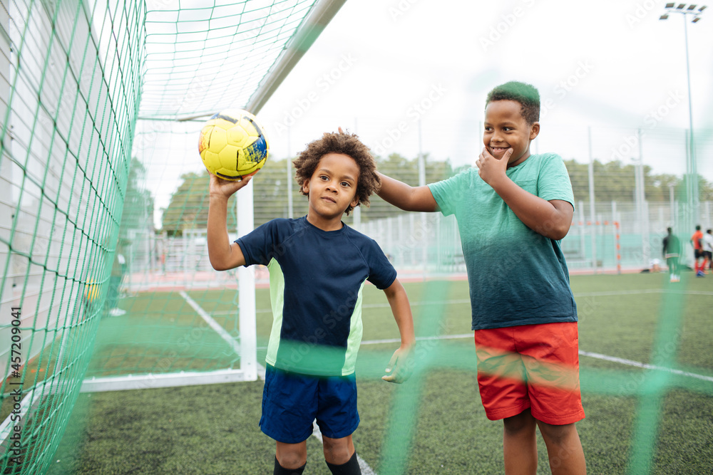 Little boy playing football. African American schoolboy at stadium