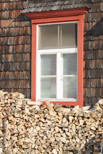 Window of a wooden house with a woodpile in winter