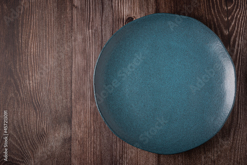 Empty plate on the wooden table. Top view of the image.