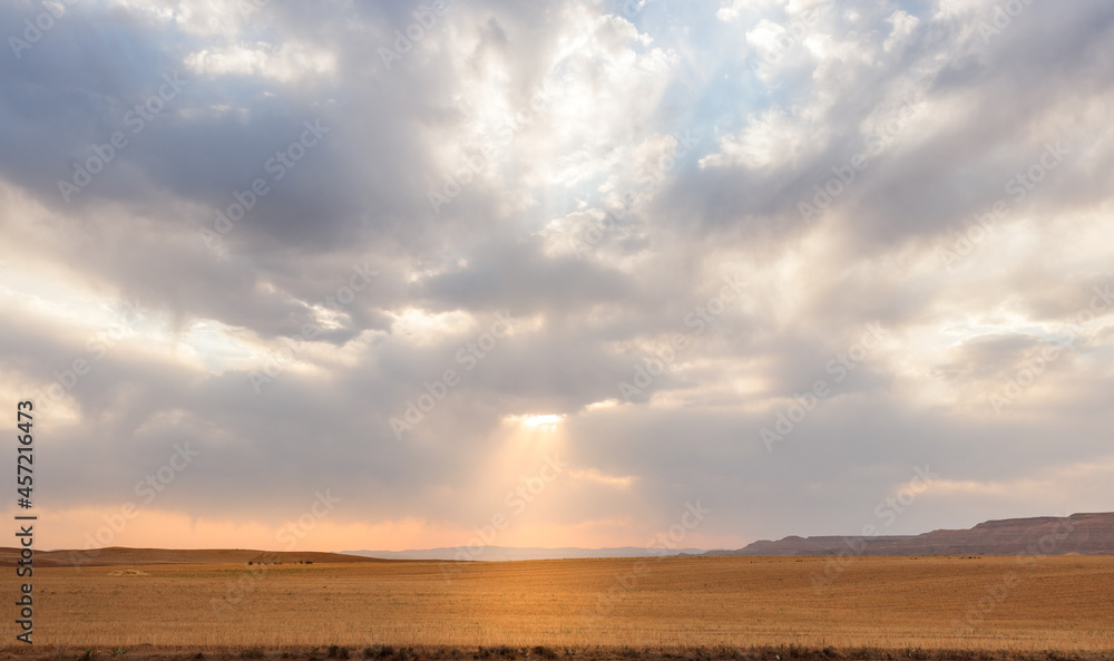 harvested Wheat field with partly cloudy sky with sunlight passing through in Kurdistan province, iran