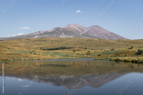  Beautiful landscape. Yellow hills mountains and small lake and river under blue sky. 