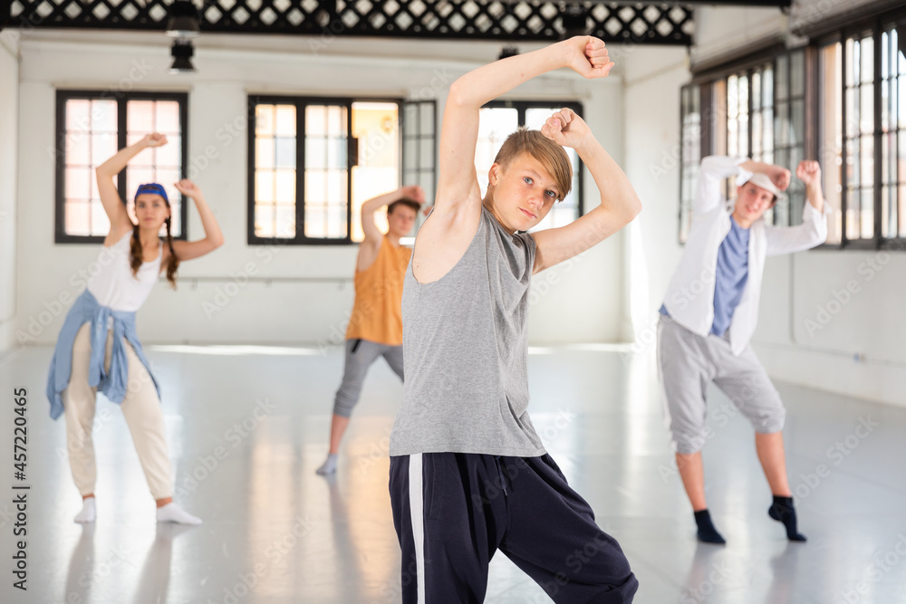 Fototapeta premium Teenage boy practicing hip hop moves with friends at group dance class
