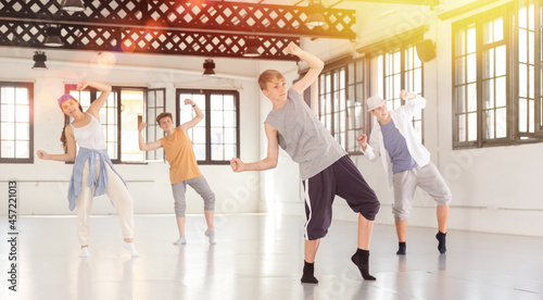 Group of teenagers training at dance class, practicing hip hop moves