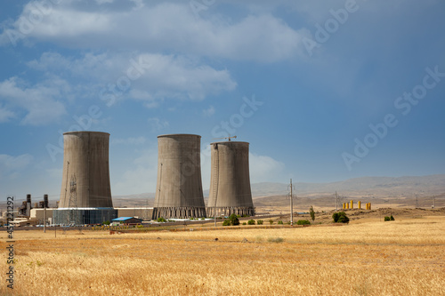 Nuclear power plant cooling towers, big chimneys beside Wheat field with partly cloudy sky in Kurdistan province, iran © AAref