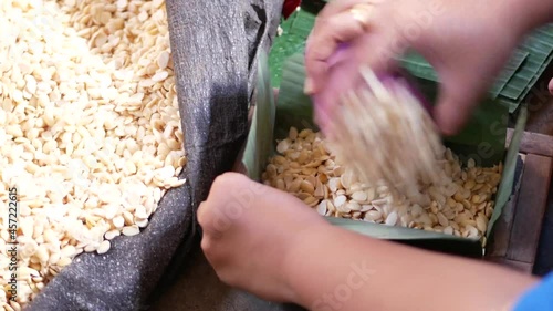 Hand of Indonesian women packing soybeans to banana leaves, javanese traditional tempeh preparation. Wrapping soybeans for fermentation.