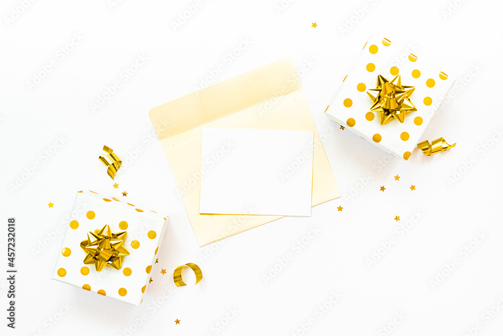 Top view of golden dotted gift boxes and open envelope with empty card on a white background. Copy space, mock-up.