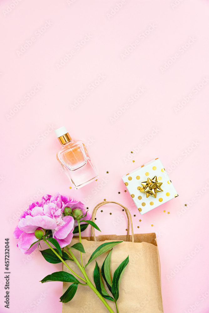 Flat lay of female cosmetics products and a gift box over pink background. Copy space.